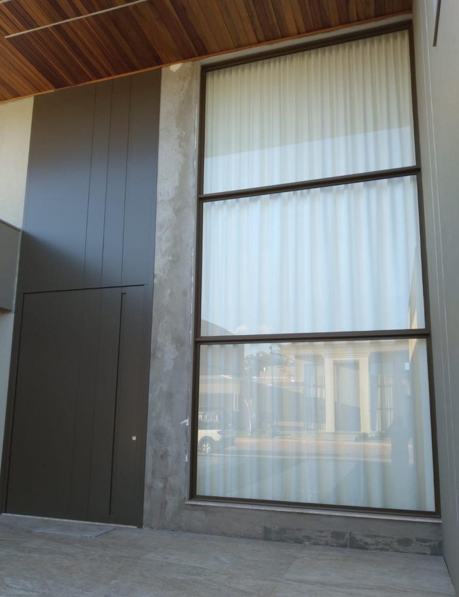 Fachada com esquadria de vidro de piso a teto ao lado do painel de entrada